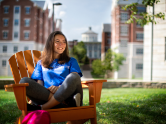 A female student sitting outdoors in a chair wearing a blue UK College of Engineering t-shirt.