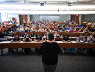 The view of a large class lecture from behind the instructor looking toward the students.