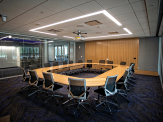 An empty meeting room with circular conference table and chairs.