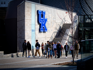 A group of prospective students touring outside of a building with the UK logo.