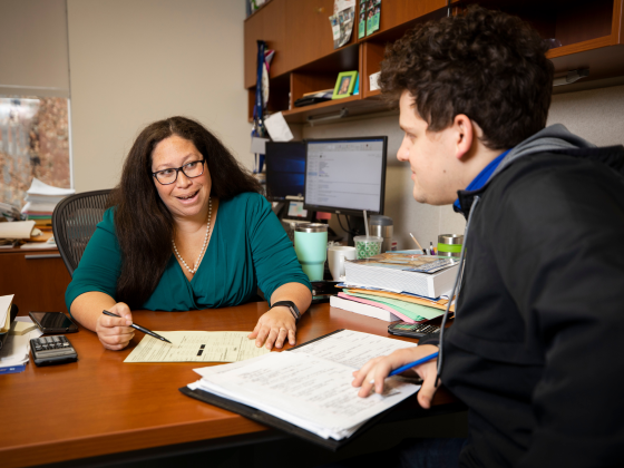 An academic advisor meeting in her office with a student.