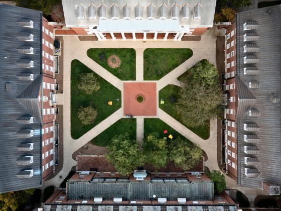 An ariel view of a courtyard shared by four buildings with sidewalks in an 'X' shaped formation.